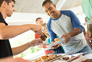 A man serves Famous Dave's people BBQ buffet style