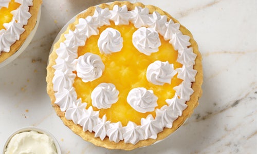 Lemon Supreme pie filled with yellow lemon curd, topped with a fancy whipped cream design