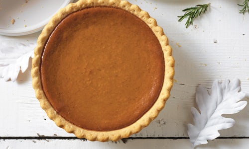 A whole Pumpkin Pie on a white table