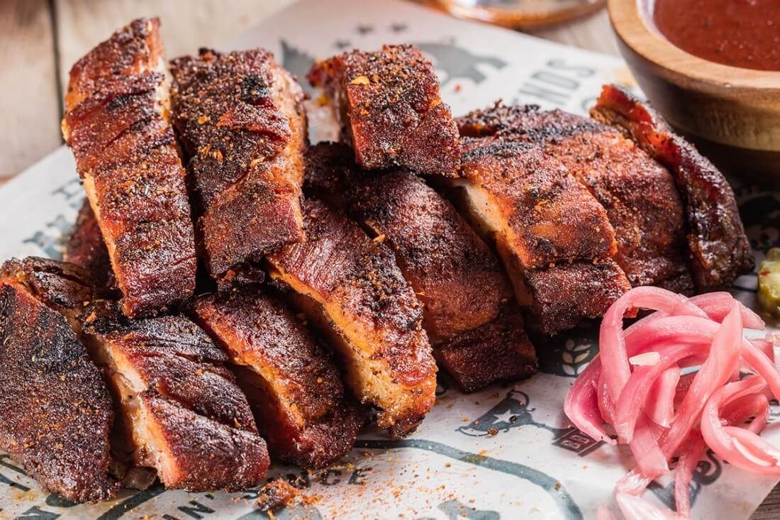 A huge piece of Famous Dave's Texas Beef Brisket, sliced up, with a side of pickled onions