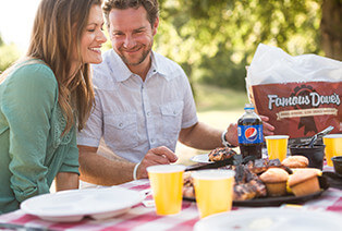 Two people eating Famous Dave's BBQ on a picnic table