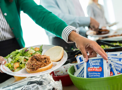 woman grabbing a Famous Dave's BBQ sauce packet to put on her sandwich