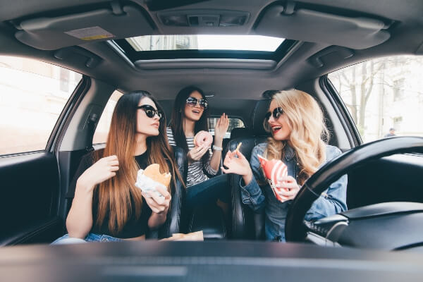 A group of friends shares food while on a road trip.
