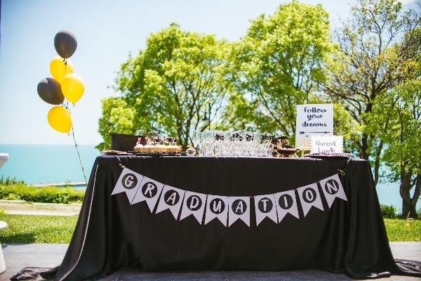 A graduation party table is set up with signs, ballons, and more.