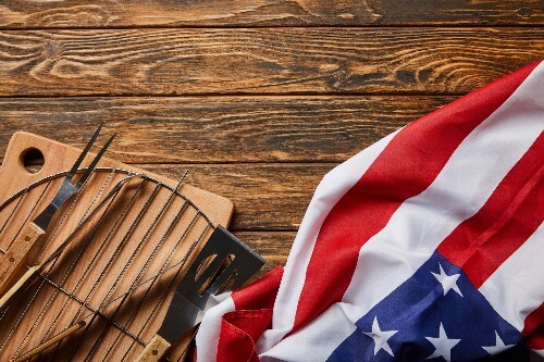 A U.S. flag representative of Veteran's Day is on a table next to BBQ tools.